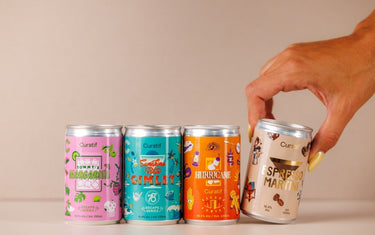 Four cans of Curatif in a row with a hand reaching down to pick up the can on the far right